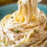 A bowl of silky spaghetti coated in a glossy cream cheese sauce with fresh parsley