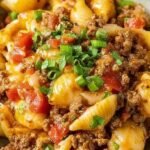 A skillet filled with creamy taco pasta shells, melted cheese, and fresh cilantro garnish.