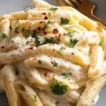 A bowl of creamy penne pasta with garlic, parmesan, and fresh parsley.