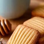 A plate of soft Italian honey cookies glazed with honey and topped with colorful nonpareil sprinkles