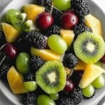 A vibrant bowl of green honeydew, kiwi, grapes, and apples tossed in a lime-mint dressing.