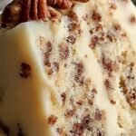 A three-layer butter pecan cake with creamy frosting and toasted pecans on top