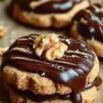 Golden espresso walnut shortbread cookies dipped in glossy dark chocolate ganache on a cooling rack.