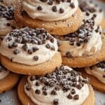 A platter of soft cannoli cookies topped with white ricotta cream, mini chocolate chips, and crushed pistachios.