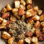 Golden crispy potato cubes tossed with fresh cilantro, garlic, and red chili in a skillet.