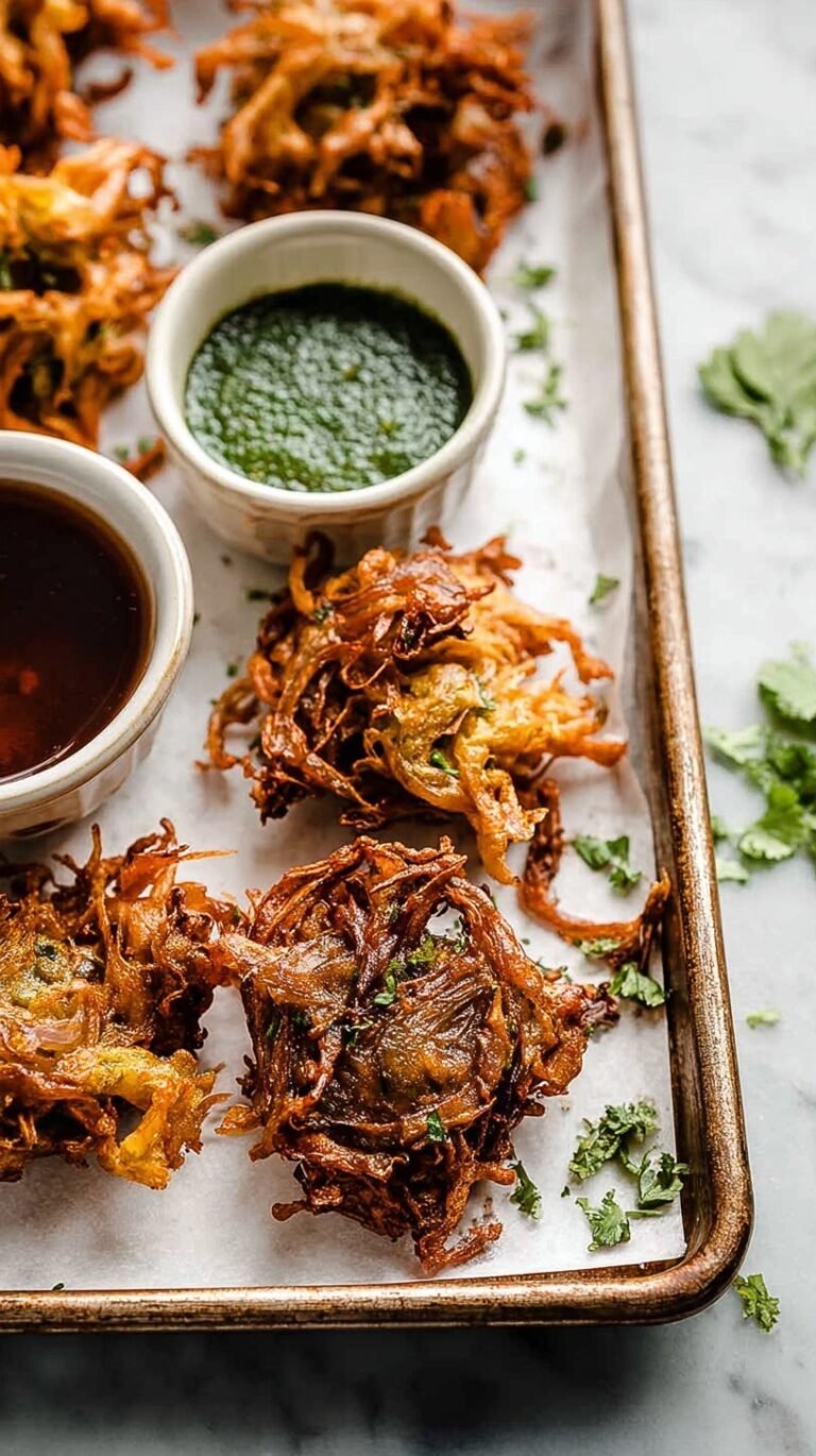 A platter of golden brown, crispy Indian vegetable pakoras served with green chutney.