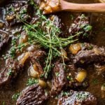 A tender cider pot roast served on a platter with glazed carrots and caramelized onions.