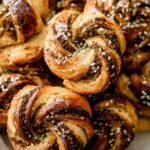 Golden brown twisted puff pastry sticks coated in green za'atar spice blend on a baking sheet.