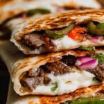 Golden brown chipotle steak quesadillas filled with melted cheese, peppers, and onions on a wooden board.