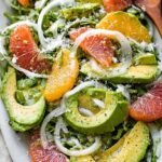 A vibrant Avocado Fennel Citrus Salad on a white platter with orange segments and shaved fennel.