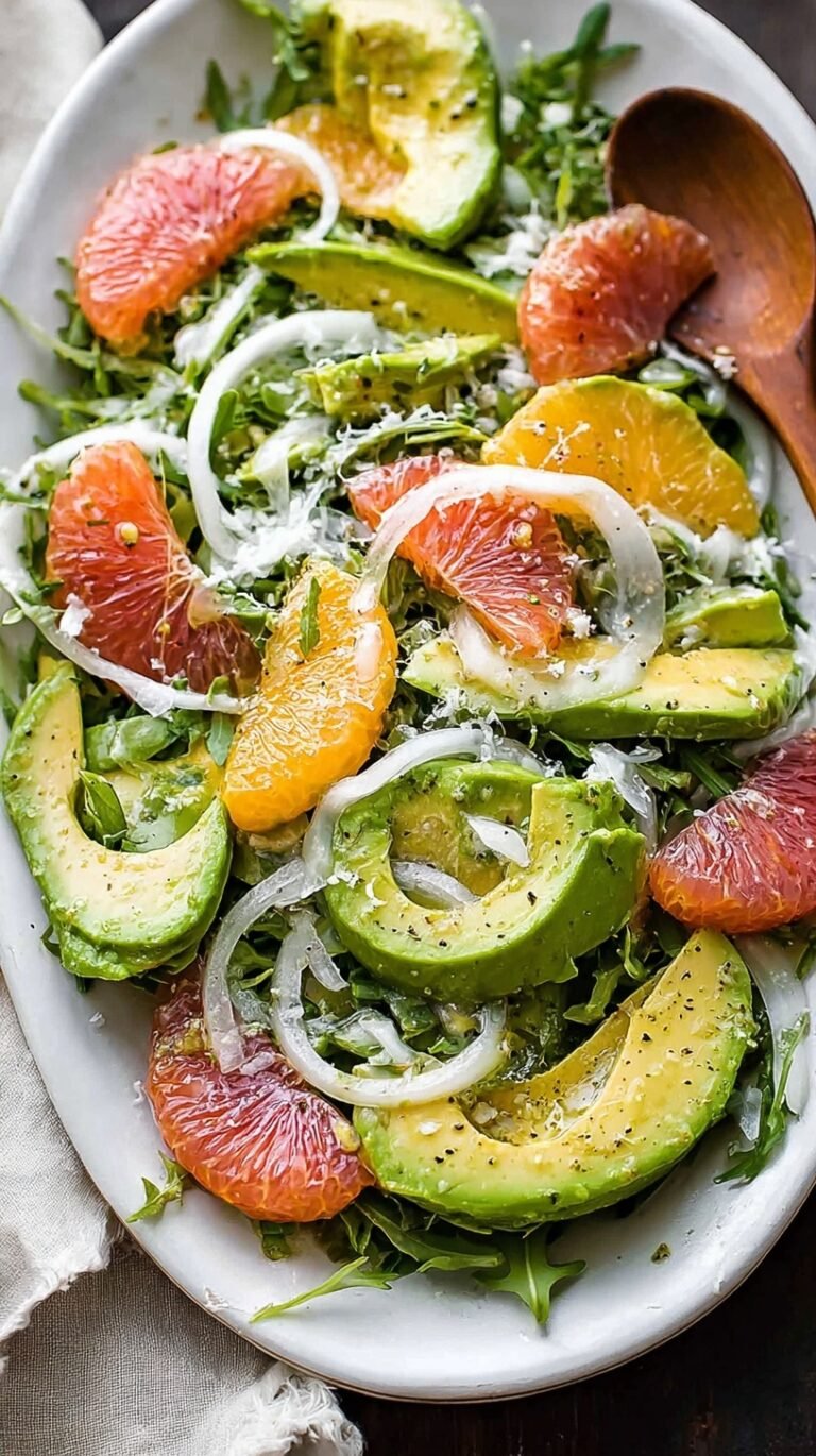 A vibrant Avocado Fennel Citrus Salad on a white platter with orange segments and shaved fennel.