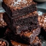 Close up of sliced fudgy chocolate brownies with a crackly top on a cooling rack