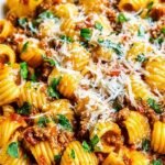 A skillet filled with cheesy Mexican-inspired pasta, ground beef, corn, and black beans garnished with cilantro.