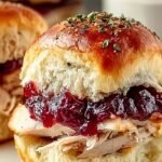 A tray of golden brown Cranberry Turkey Sliders topped with poppy seeds and melted Havarti cheese.