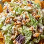 A cast iron skillet filled with beef and cabbage mixture topped with melted cheese and Frito chips