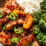 Golden pan-seared chicken breasts coated in a glossy peach and jalapeno glaze garnished with fresh cilantro