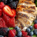 A vibrant berry chicken salad topped with strawberries, blueberries, and pecans in a large bowl.
