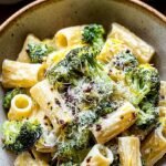 A bowl of creamy lemon ricotta pasta with green broccoli florets and parmesan cheese