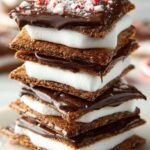 Toasted indoor peppermint smores with melted dark chocolate and crushed candy canes on a baking sheet.