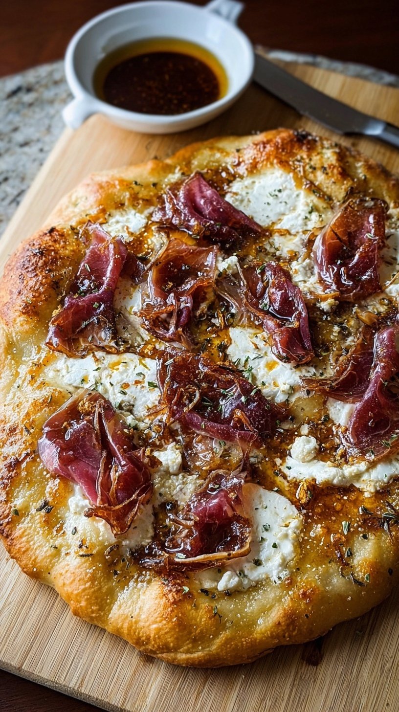 Gourmet white pizza topped with thin slices of beef prosciutto, fresh basil, and a drizzle of hot honey.