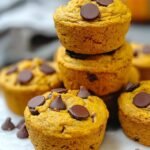 A batch of golden gluten-free pumpkin muffins with melted chocolate chips in a muffin tin