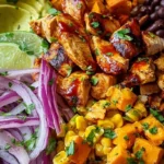 A vibrant meal prep container filled with roasted sweet potatoes, BBQ shredded chicken, black beans, and corn.