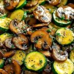 Sautéed sliced zucchini and cremini mushrooms in a cast iron skillet with fresh herbs