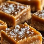 A stack of golden brown salted caramel butter bars with a gooey caramel center and a sprinkle of sea salt on top.