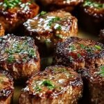 Sizzling golden-brown steak bites in a creamy white parmesan sauce with fresh parsley garnish in a cast iron skillet