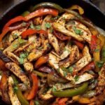 Sizzling chicken strips and colorful bell peppers in a cast iron skillet