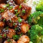 Crispy glazed salmon cubes in an air fryer basket with green onions