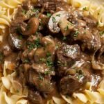 A bowl of healthy beef stroganoff with mushrooms and whole wheat noodles garnished with parsley