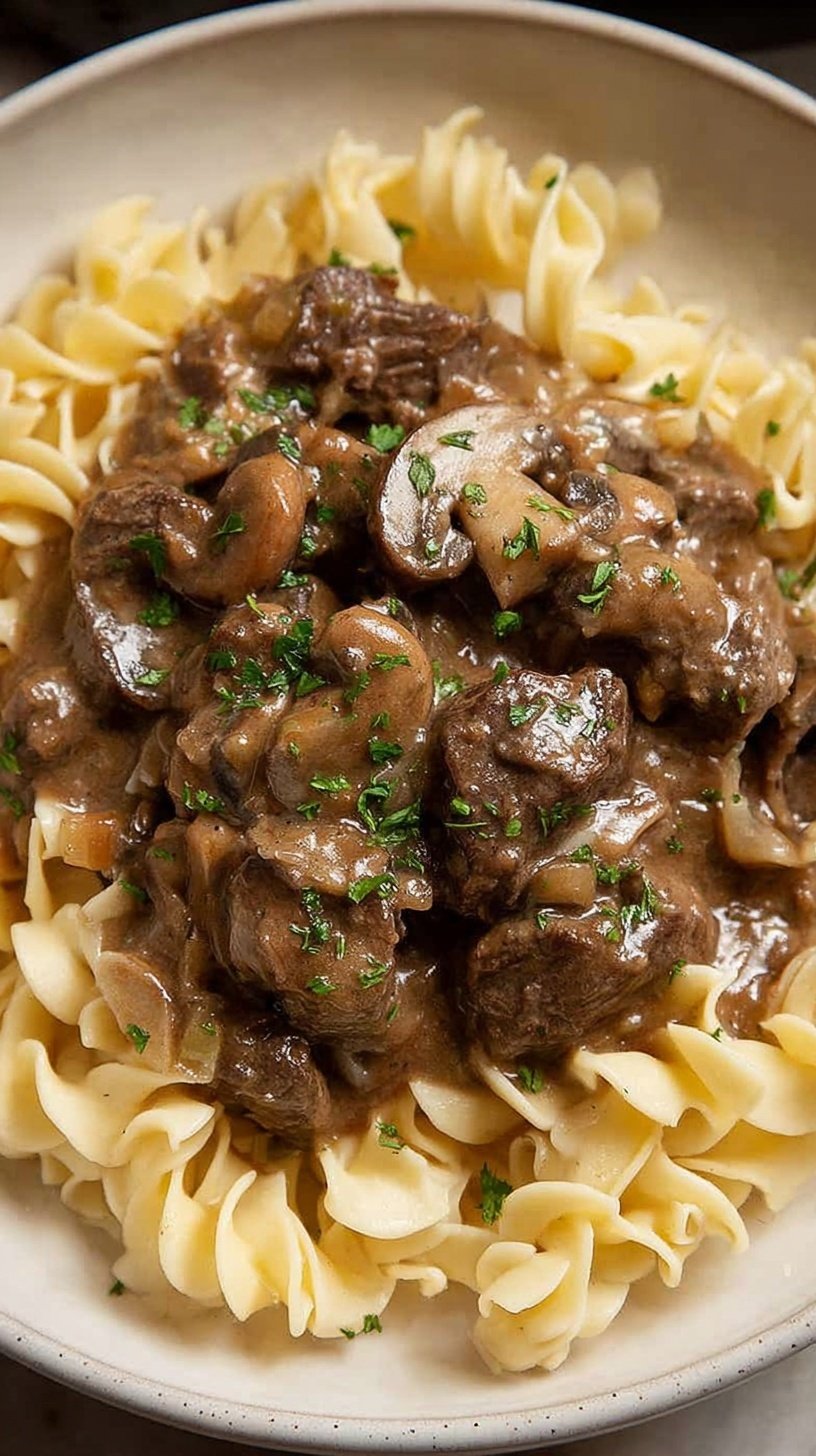 A bowl of healthy beef stroganoff with mushrooms and whole wheat noodles garnished with parsley