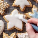 A tray of golden brown almond flour sugar cookies cut into star and heart shapes on a cooling rack.