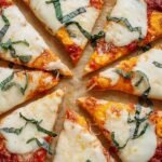 A golden brown whole wheat pizza topped with green peppers, red onions, and spinach on a baking sheet.