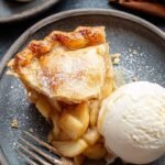 A golden brown gluten-free apple pie with a flaky double crust and sliced apples inside.