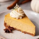 A smooth and creamy gluten-free pumpkin cheesecake on a serving platter with a spiced graham cracker crust.