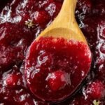 A bowl of vibrant red cranberry sauce with orange zest on top