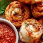 Golden brown crispy pizza rolls arranged on a white plate with a side of marinara sauce.