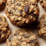 A stack of golden brown chewy oatmeal raisin cookies with melting chocolate chips on a wire rack.