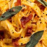 A bowl of pasta coated in a smooth, golden butternut squash sauce with fresh sage leaves.