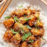 Glazed pieces of Air Fryer Teriyaki Chicken topped with sesame seeds and green onions