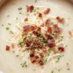 A bowl of smooth, creamy cauliflower leek soup topped with fresh thyme and black pepper.