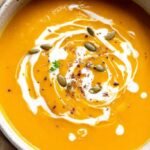 A bowl of smooth orange carrot and butternut squash soup with ginger