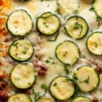 A bubbling 9x13 baking dish filled with layers of sliced zucchini, savory ground beef, and melted golden mozzarella cheese.