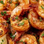 Golden-brown seasoned shrimp served on a platter with fresh lemon wedges