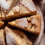 A golden brown gluten-free apple cake in a bundt shape topped with fresh apple chunks.