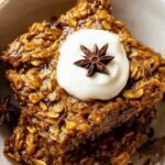 A golden brown dish of pumpkin baked oatmeal topped with pecans and a drizzle of syrup