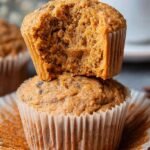 A stack of golden brown healthy banana pumpkin muffins on a wire cooling rack.