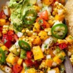 A colorful bowl of Corn Mango Avocado Salsa with chips